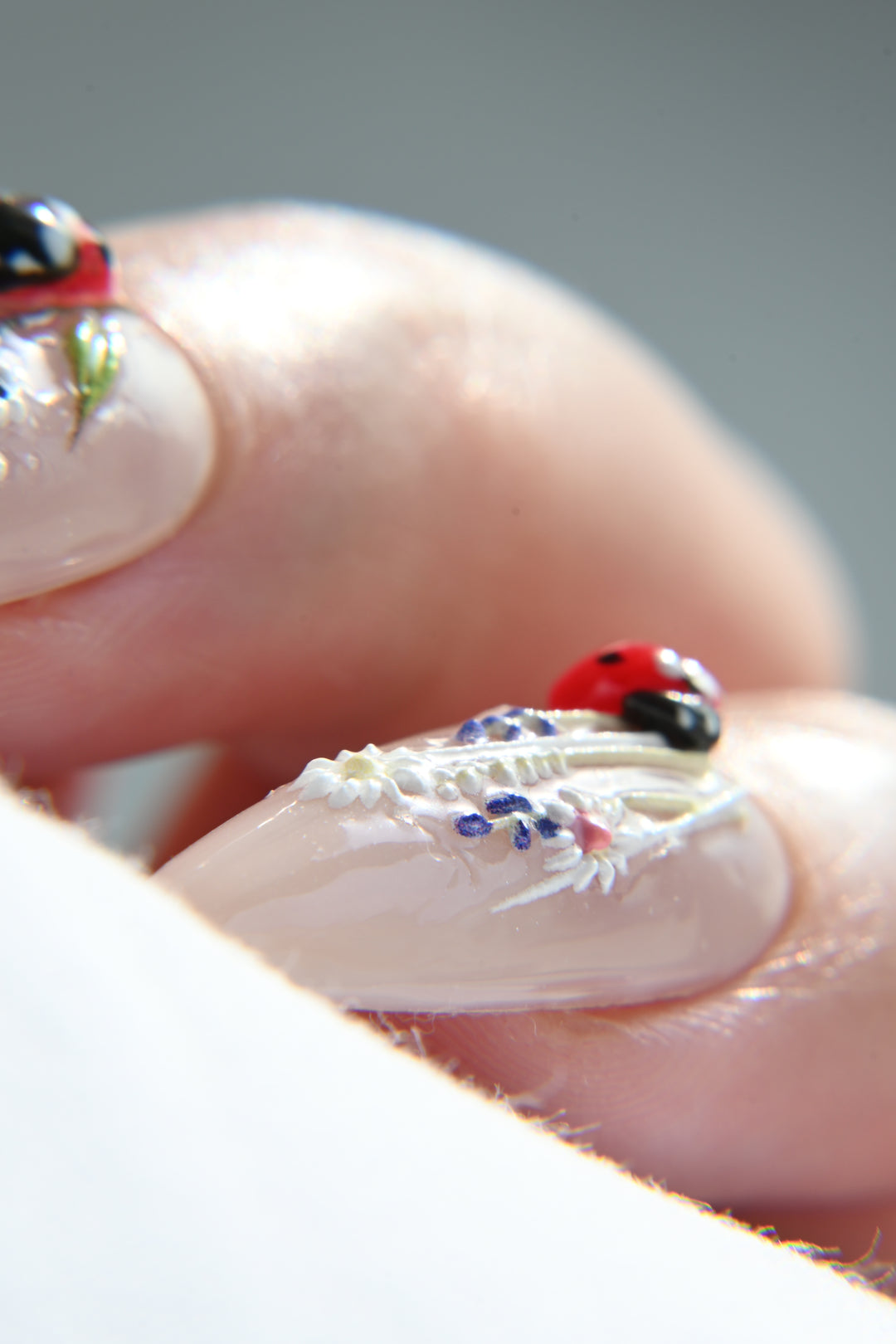 Close-up of a hand with detailed nail art featuring ladybugs.